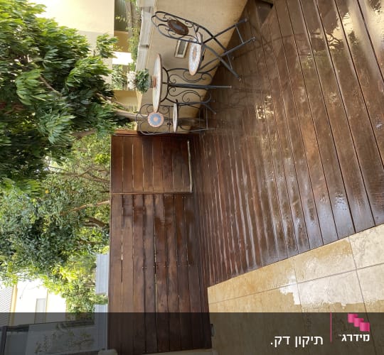 דק עץ רטוב עם שולחן וכיסאות בגינה